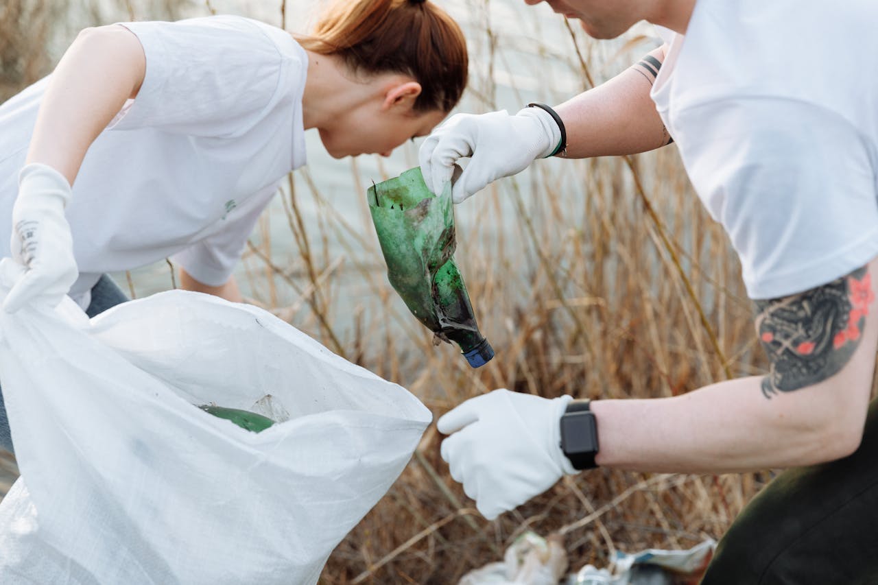 Two volunteers picking up litter outdoors to promote environmental awareness.